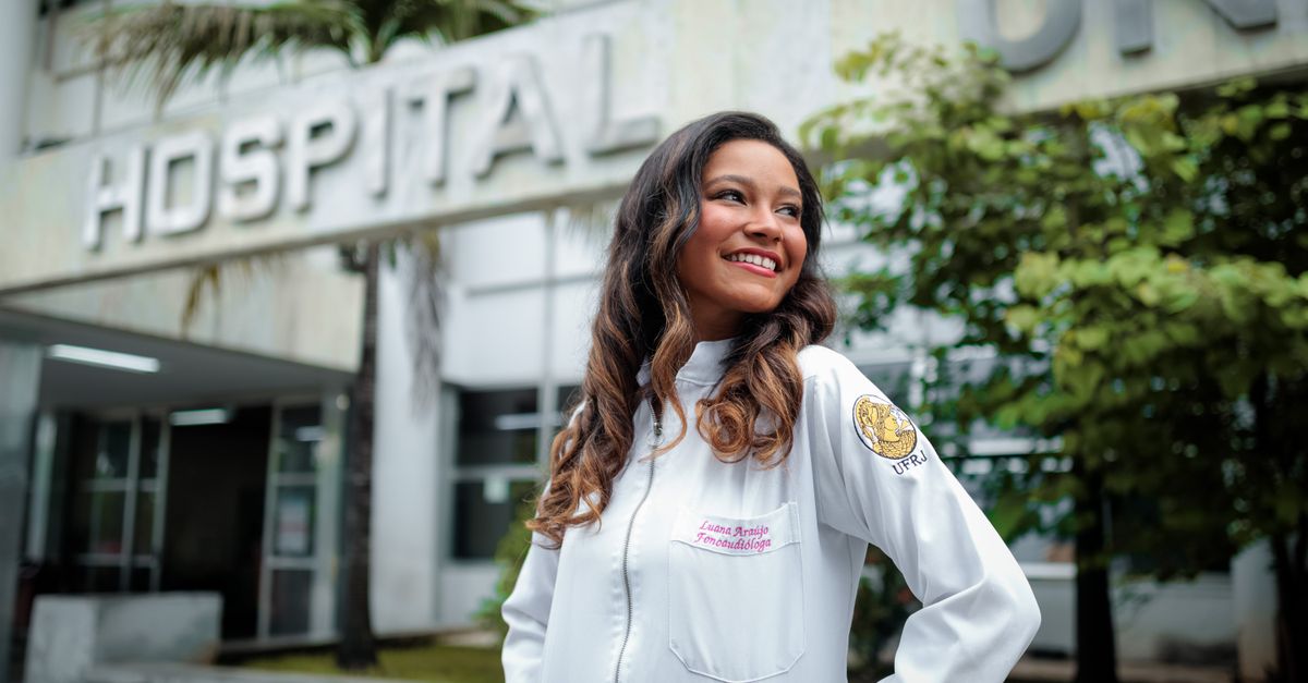 young doctor in white coat looking confident in hospital corridor