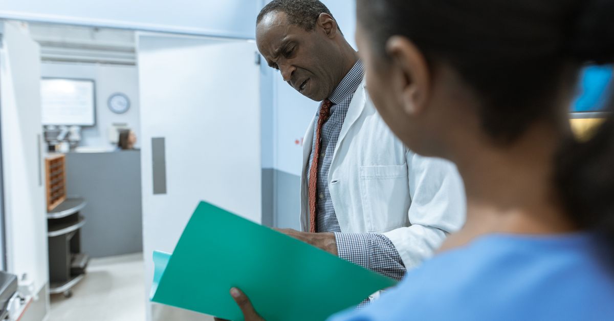 Equipe médica em reunião hospitalar discutindo prontuário e protocolos clínicos