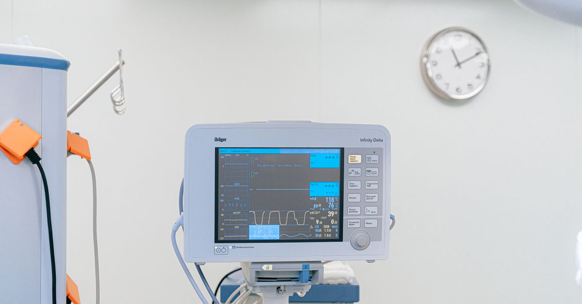 Monitor multiparamétrico em sala hospitalar com relógio na parede