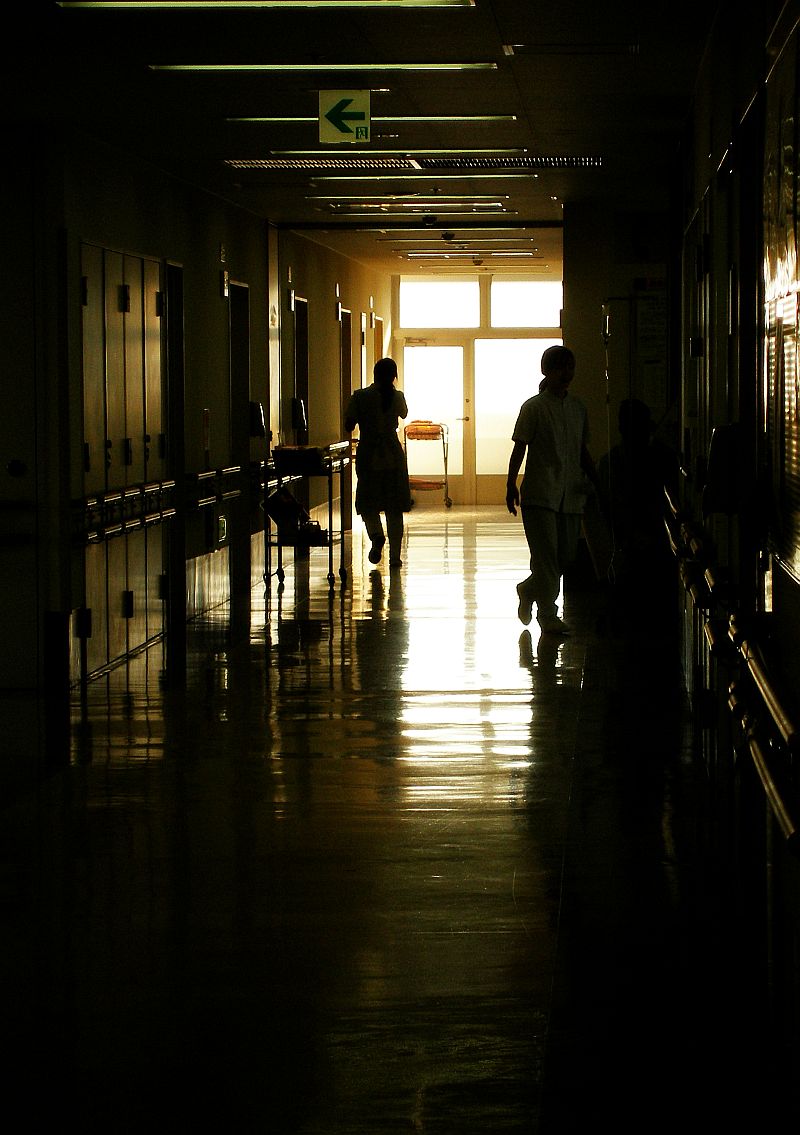 Médico plantonista em corredor de hospital às 4 da manhã, sob luz artificial, concentrado em prontuário