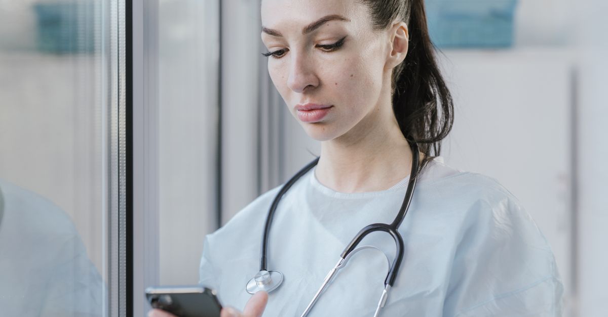 Médico segurando iPhone com notificação de plantão aparecendo na tela de bloqueio
