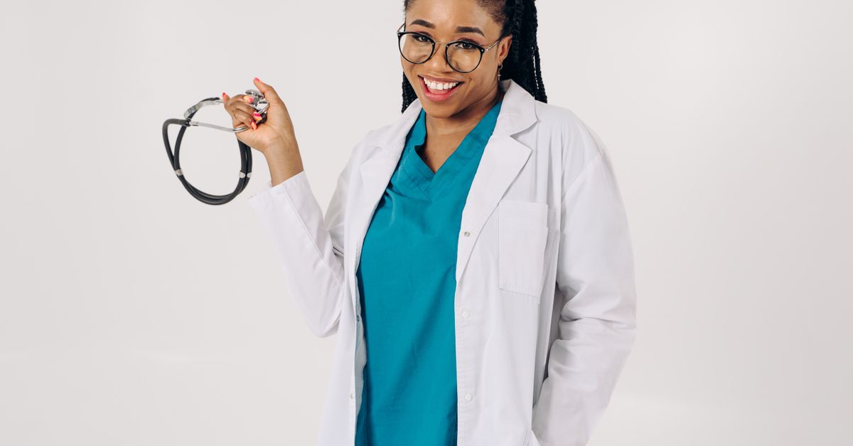 Médico jovem com jaleco branco e estetoscópio em corredor de hospital