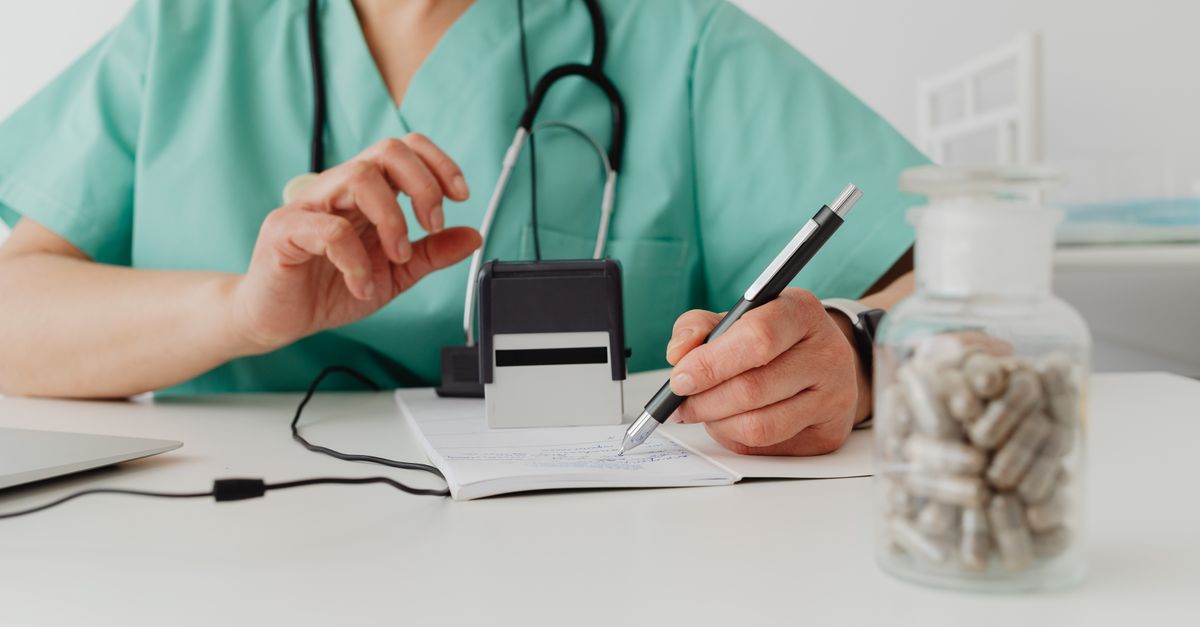 Médico particular escrevendo receita em consultório com foco na prescrição e medicamentos